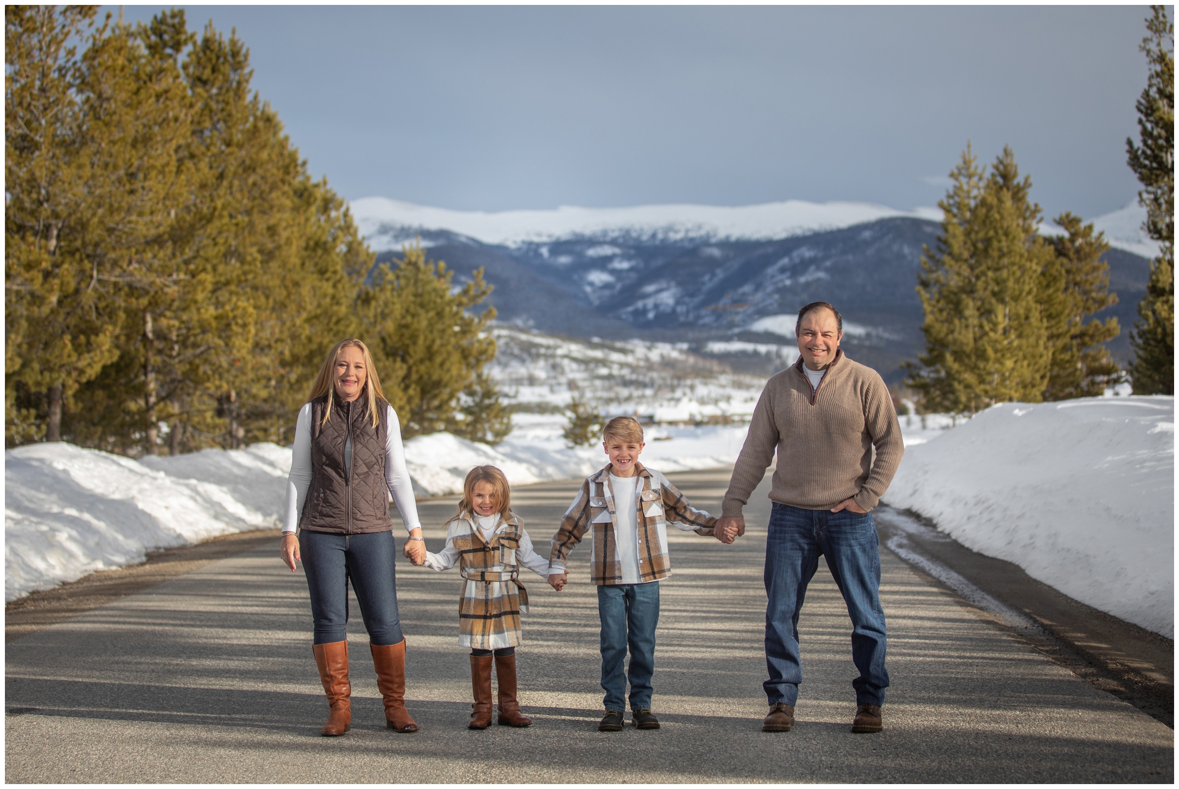 family posing on a mountain road during Winter Park snowy session at Devil's Thumb Ranch
