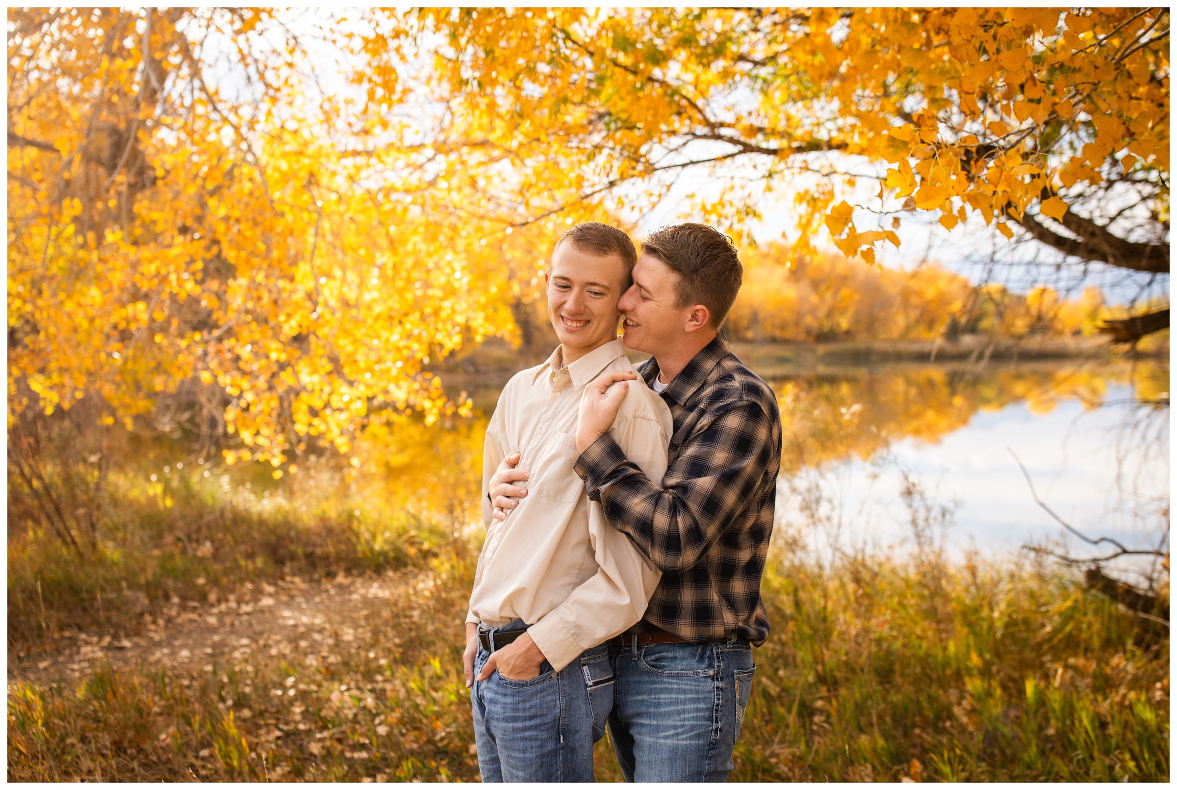 couple embracing around colorful fall foliage during Colorado same sex gay engagement session at Golden Ponds in Longmont