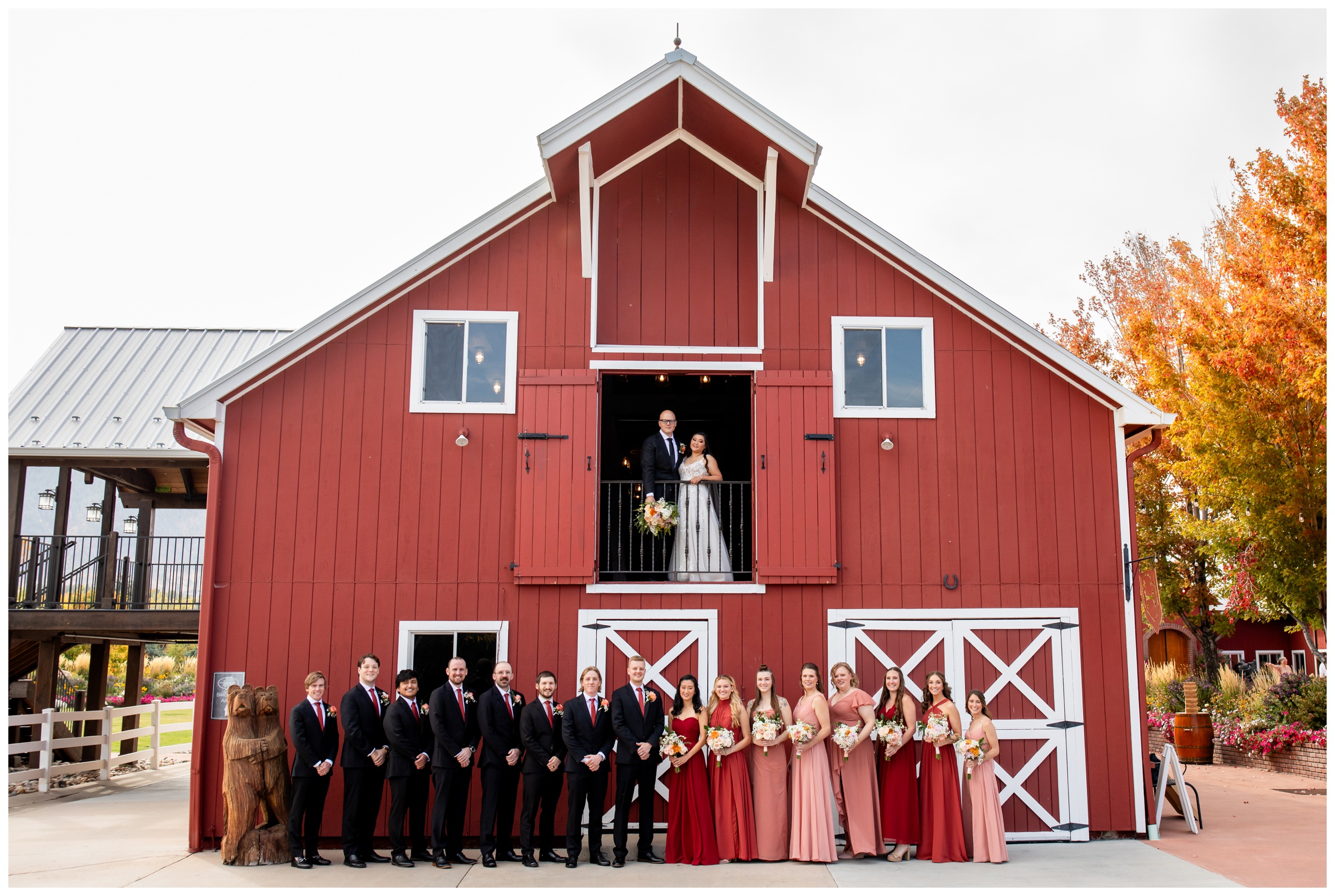 bride and groom and wedding party posing in front of red barn during Crooked Willow Farms Colorado wedding pictures