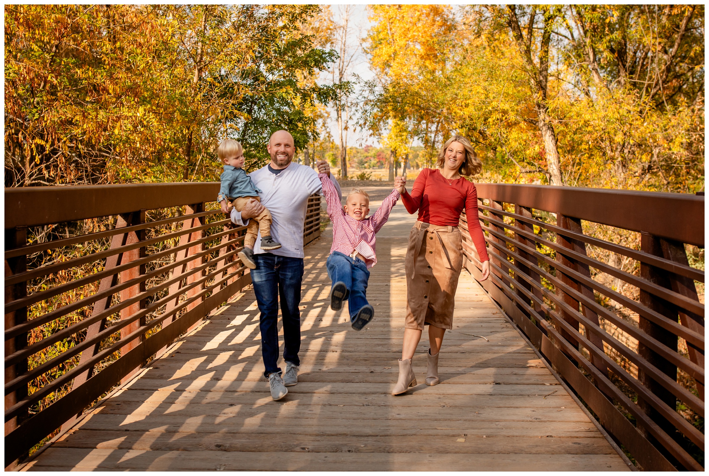 family walking on bridge at Golden Ponds in Longmont during fall mini sessions