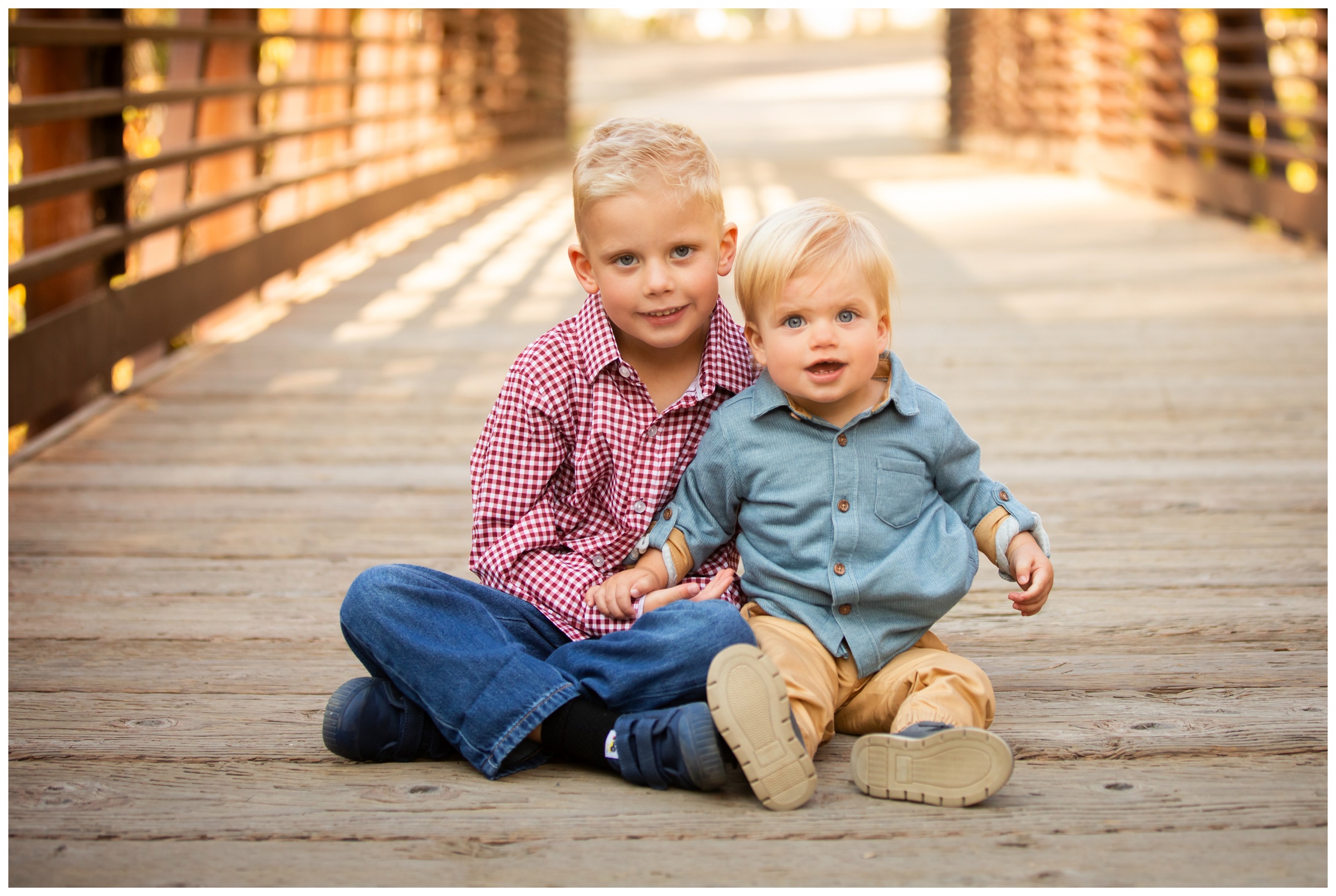 little brothers sitting on bridge during Longmont fall family mini sessions at Golden Ponds