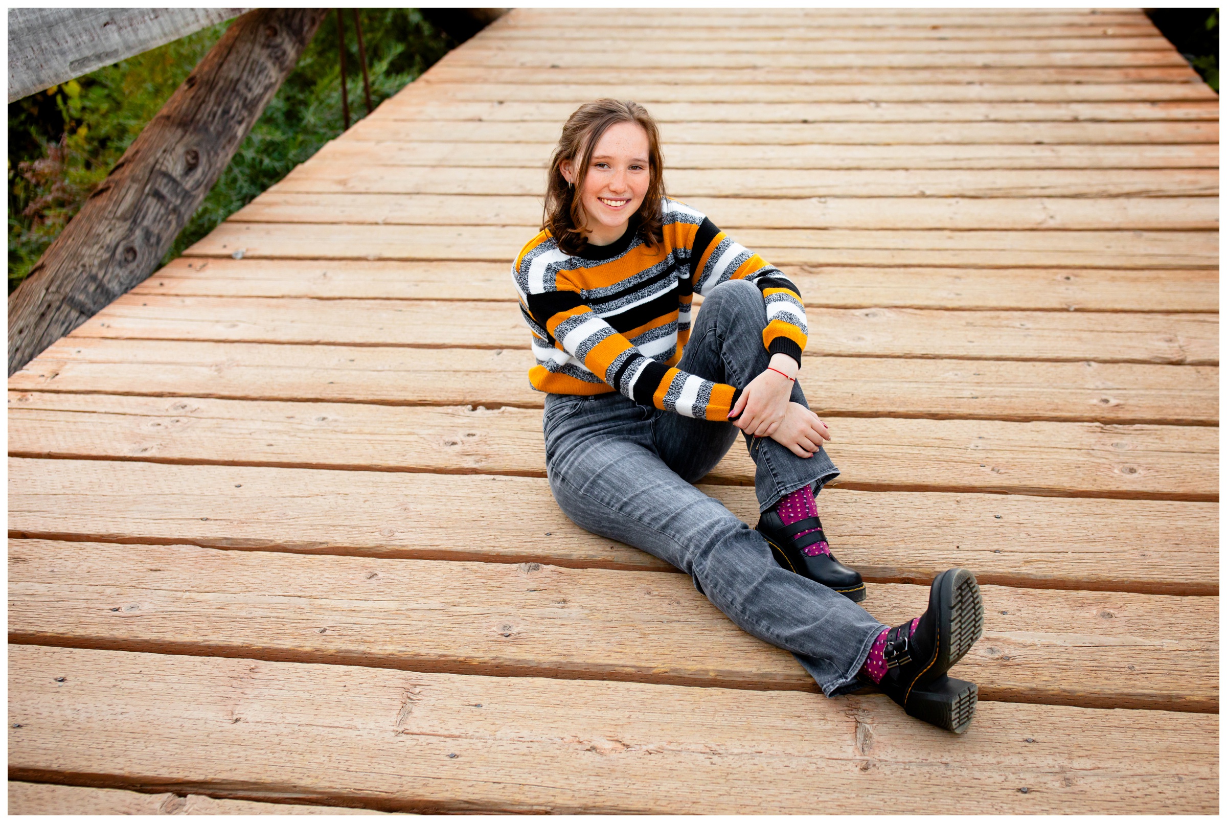 teen sitting on wooden bridge during Boulder Colorado senior pictures at South Mesa Trail