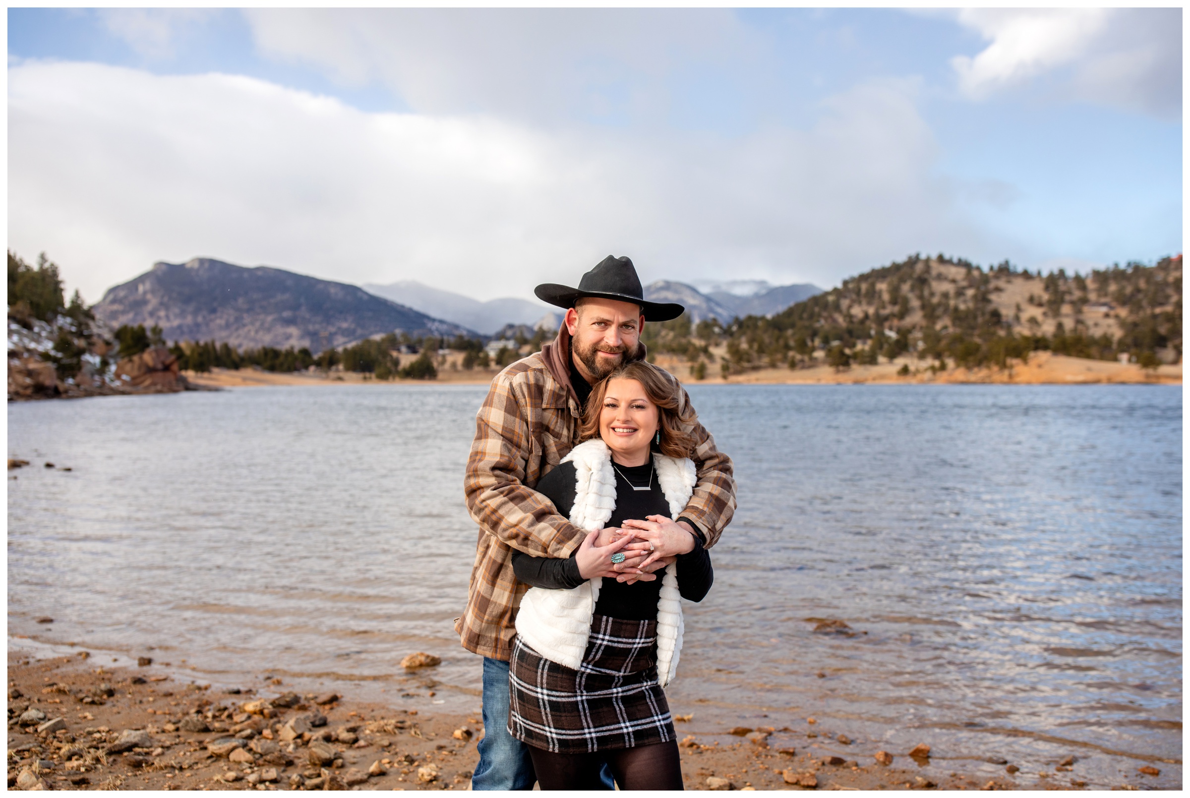 couple cuddling during winter engagement pictures in Estes Park Colorado at Mary's Lake by portrait photographer Plum Pretty Photography