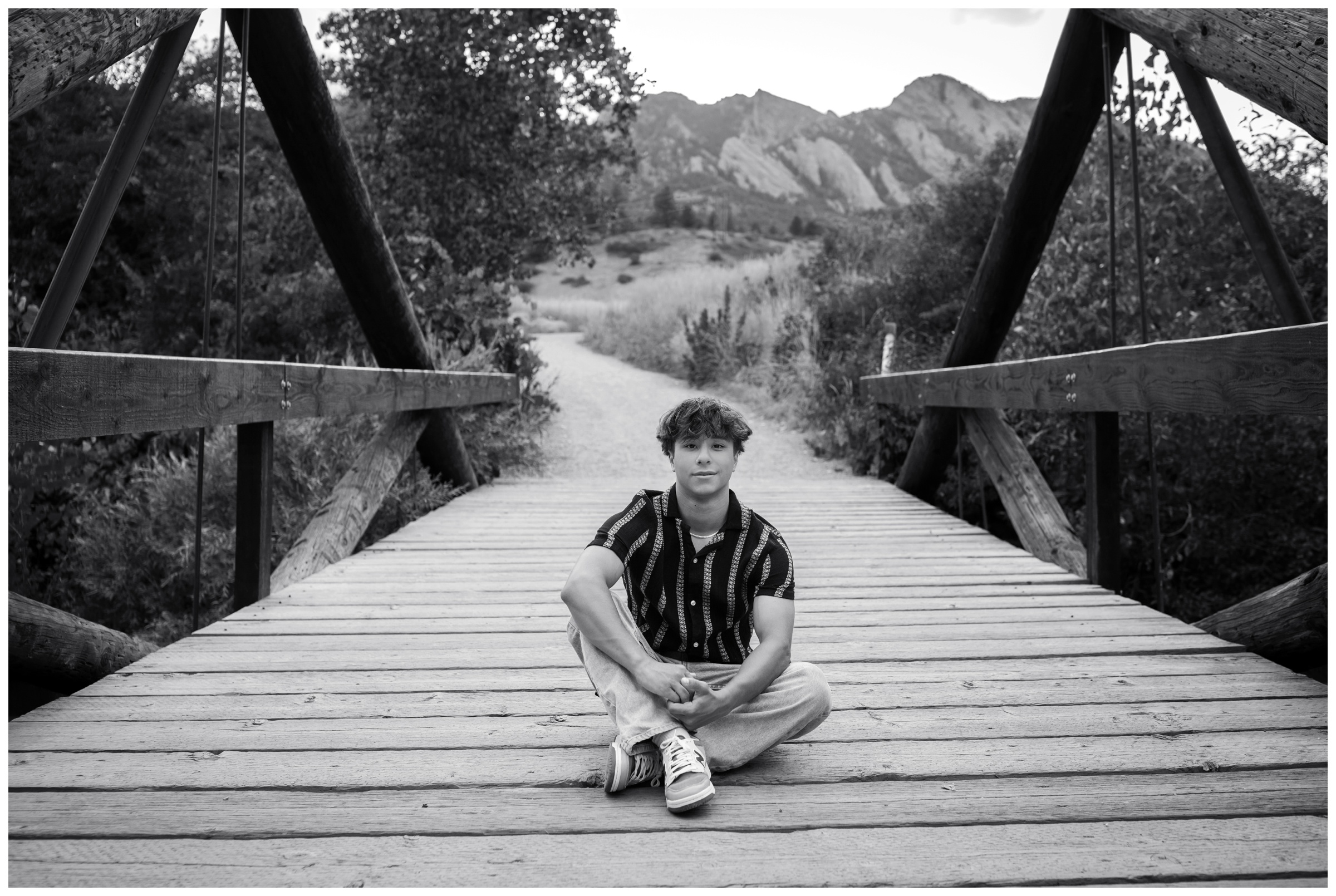 teen guy sitting on bridge during Holy Family High School Colorado senior pictures in Boulder 