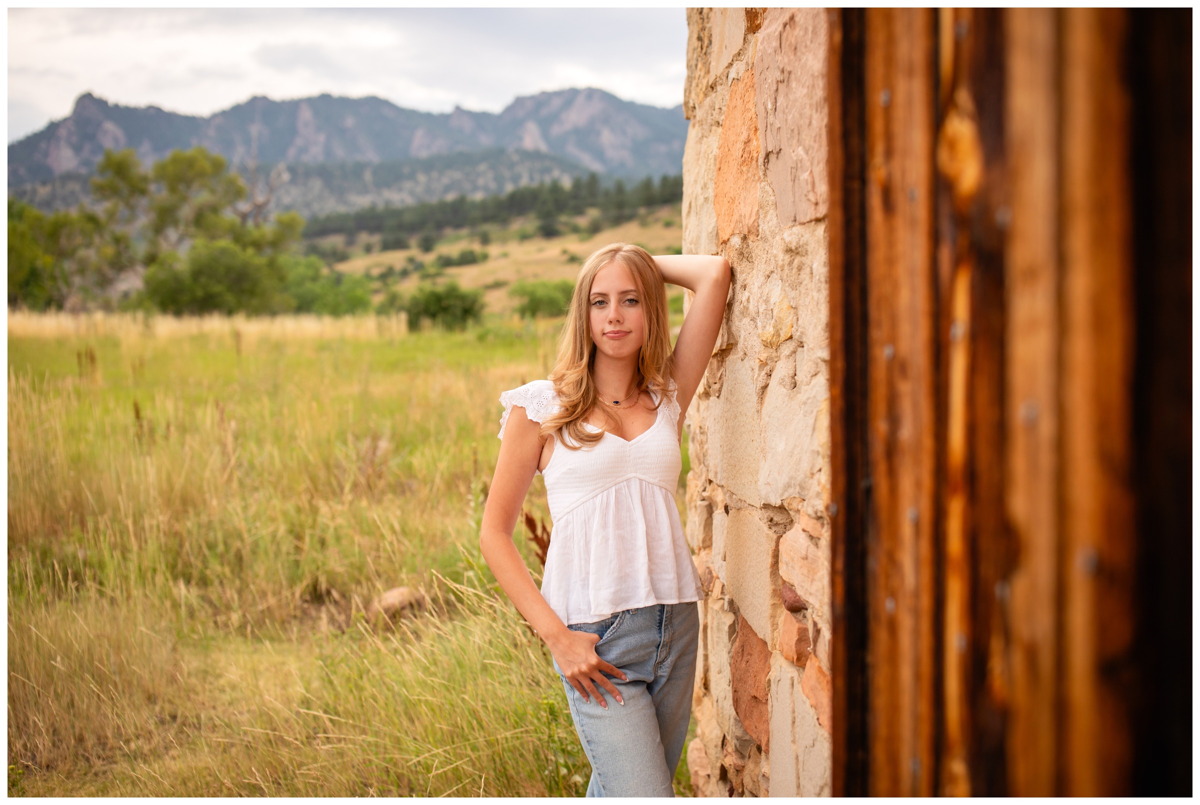 teen leaning against a stone building at South Mesa Trail during Boulder Colorado senior photos 