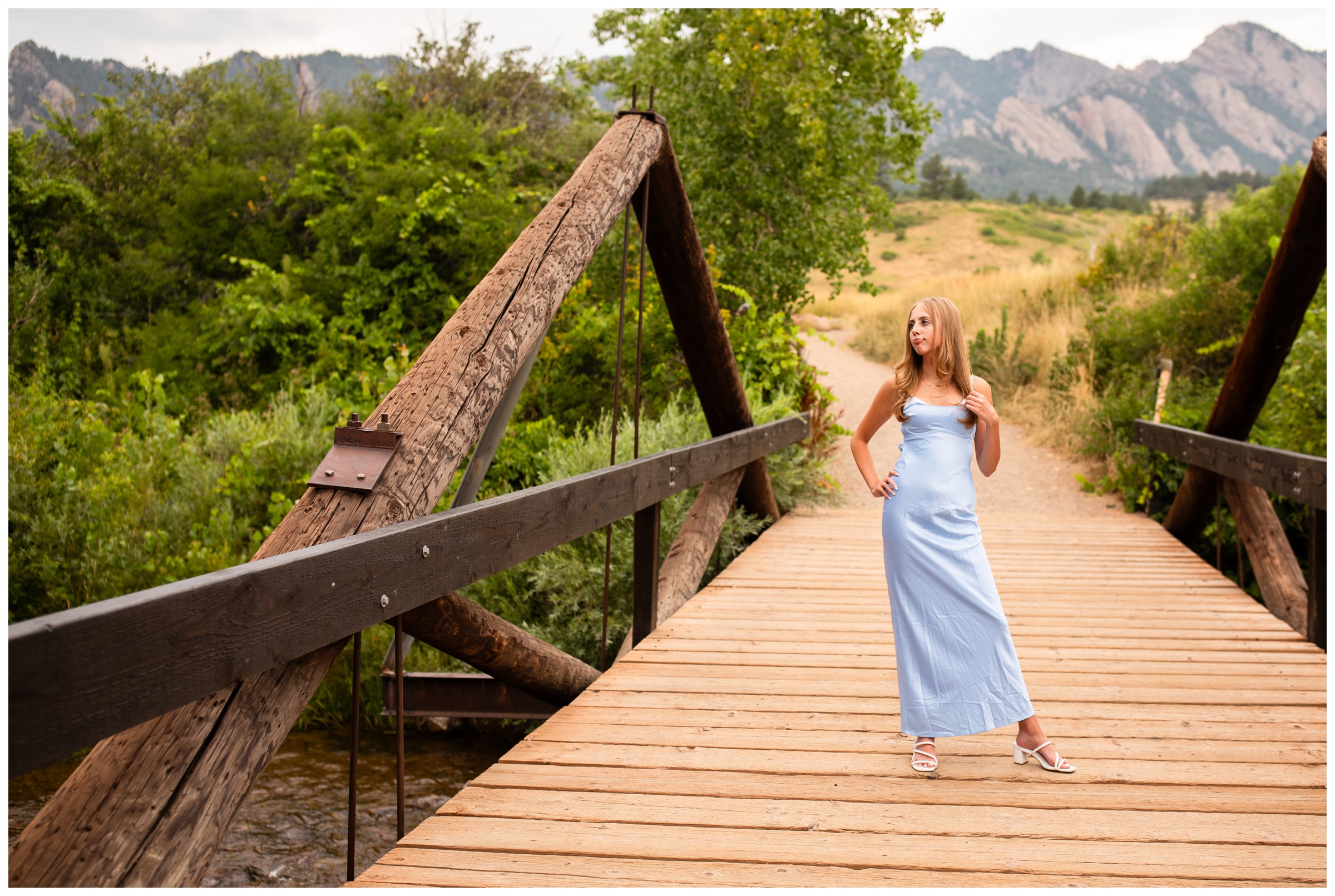 teen posing on wooden bridge in prom dress during Colorado high school portrait session 