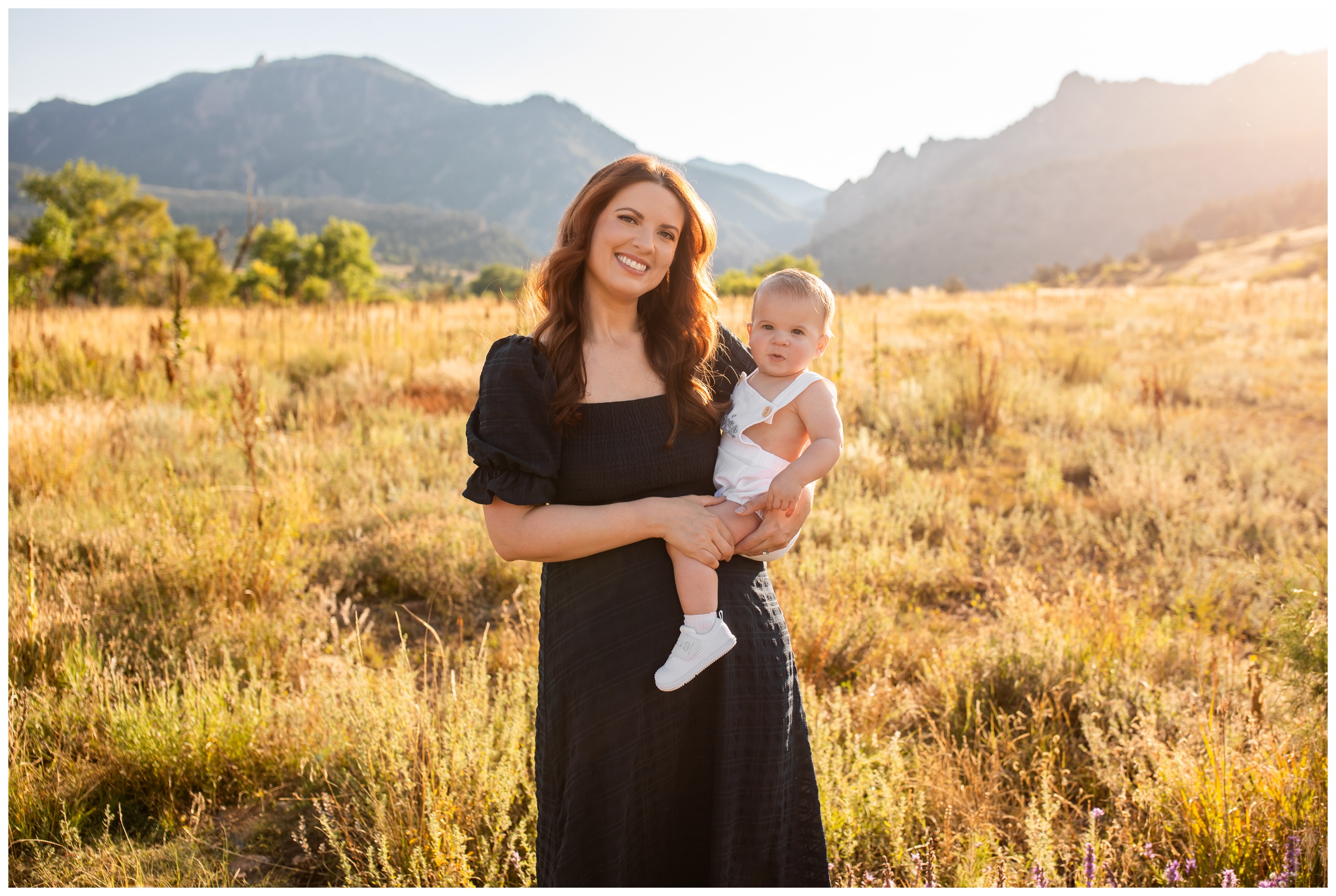 mom holding baby in mountain field during family photography session in Boulder Colorado 