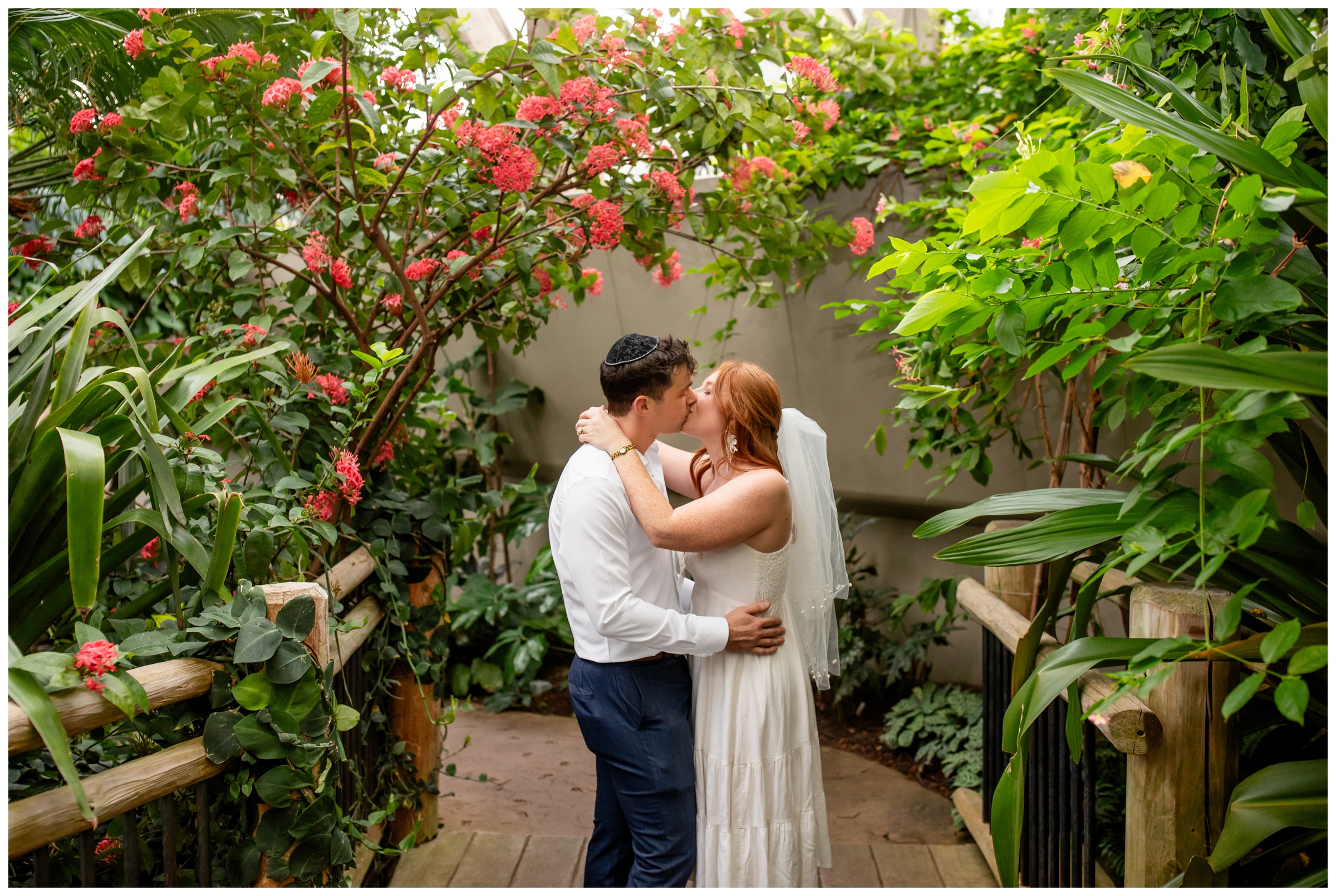 couple kissing under floral arch during self-solemnization wedding at the Denver Botanic Gardens