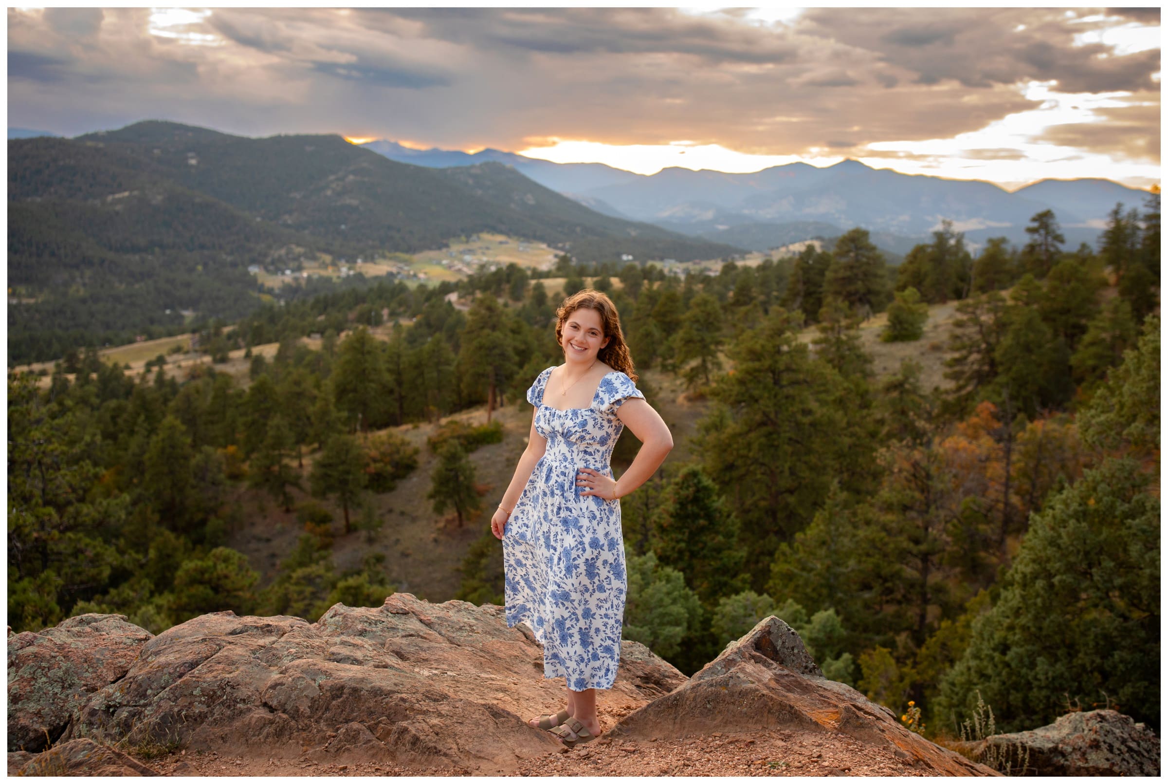 teen posing on edge of cliff during mountain senior photos at Mount Falcon West in Colorado 