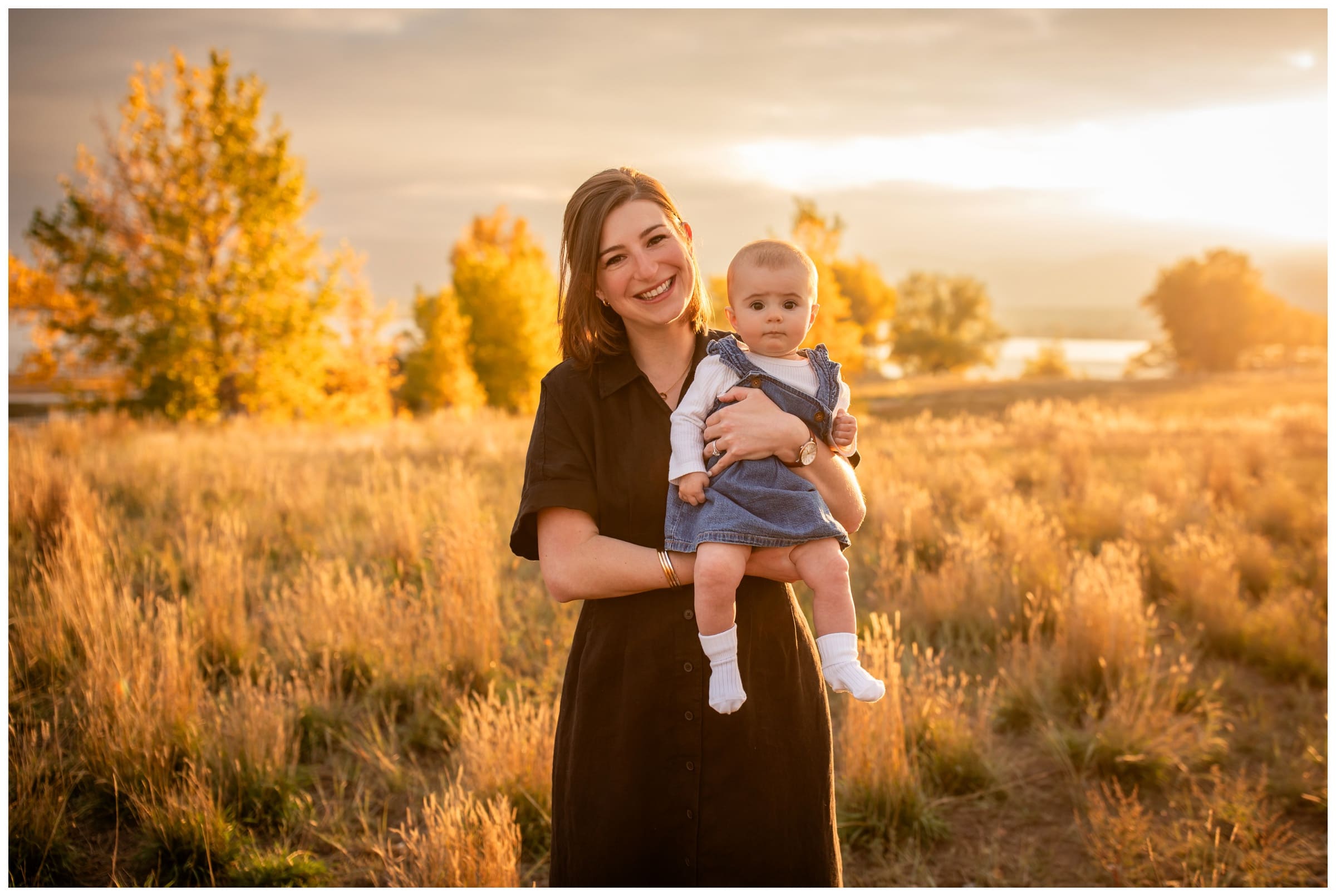 mom holding baby in field during sunset family photos in Boulder Colorado 