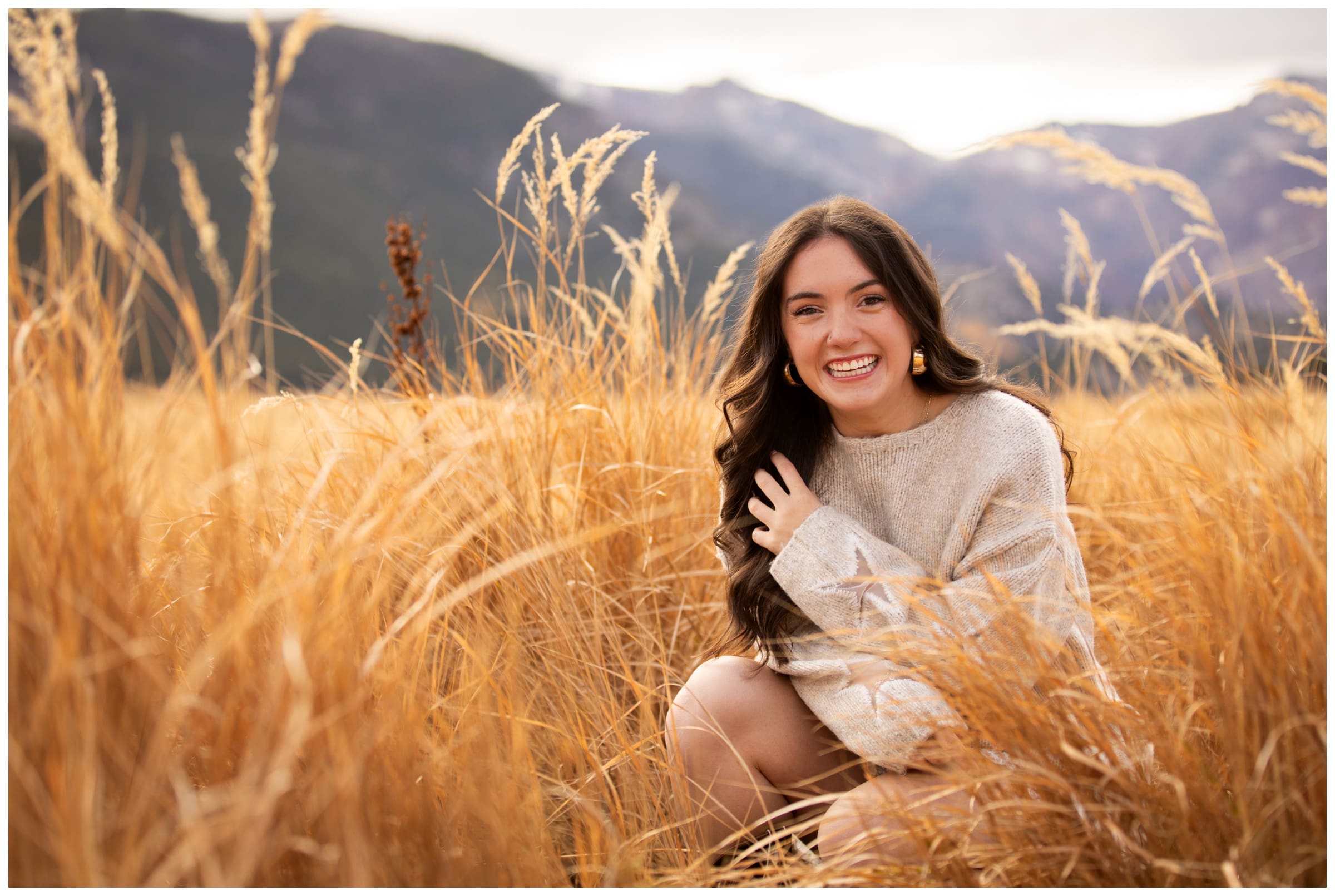 teen squatting in mountain field during Niwot High School senior portraits in RMNP