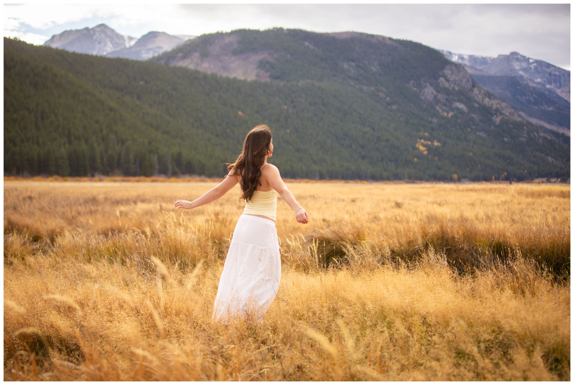teen twirling in field during photo session in Moraine Park in RMNP