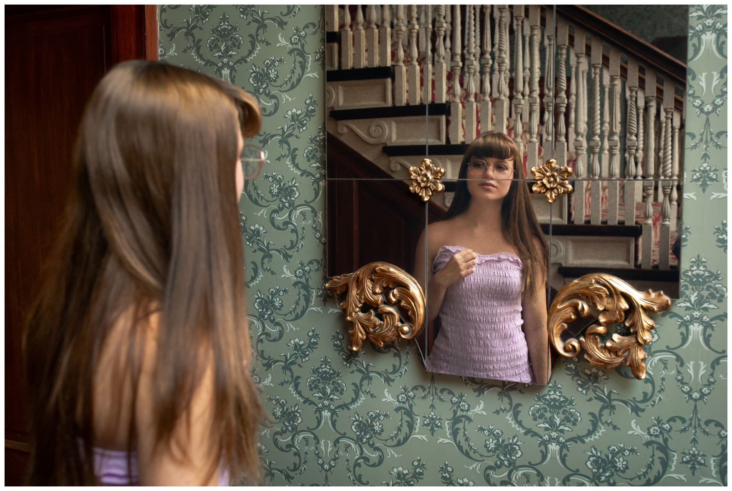 teen looking into vintage mirror during unique Colorado senior photos at the Stanley Hotel 