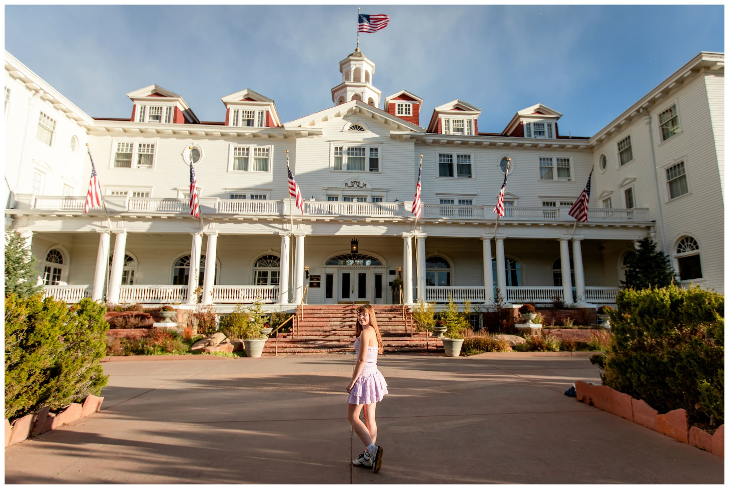 teen posing in front of the Stanley hotel during unique senior pictures in Colorado