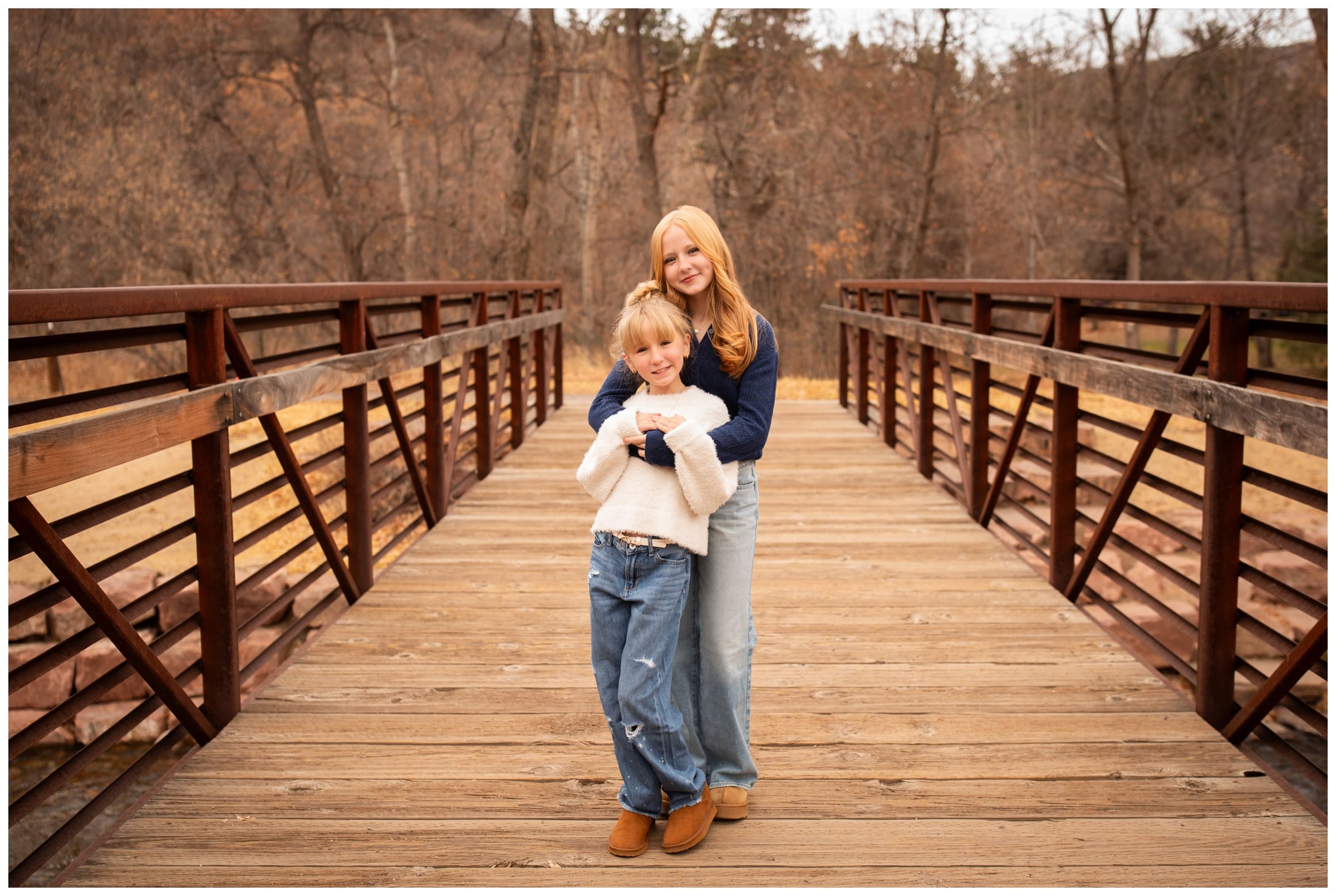 sisters hugging on bridge during Lyons Colorado fall family photography session